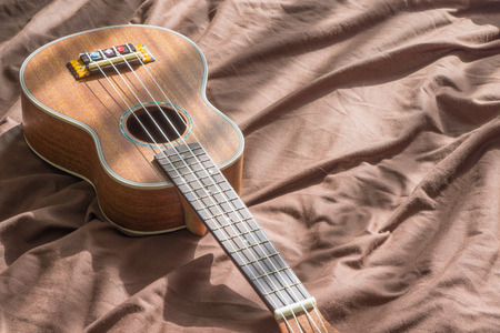 Ukulele guitar on bed background., copy space for text., girl enjoy with her ukulele. music concept....