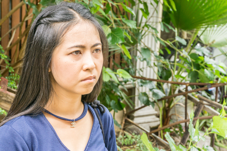 Young Asian woman in stand on street in front of a home, looking at the camera with a serious expression, Portrait of charming Asian girl in the park, copy spaceの写真素材