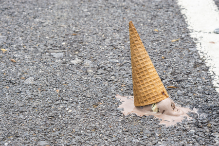 Icecream on the ground. (selective focus)., chocolate icecream cone dropped on the concrete floor and melt on ground. with copy space for text. dirty concept. lost concept.の写真素材