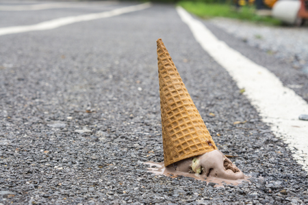 Icecream on the ground. (selective focus)., chocolate icecream cone dropped on the concrete floor and melt on ground. with copy space for text. dirty concept. lost concept.の写真素材