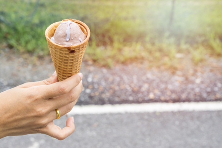Ice cream cone filled with twirled softserve in hand / public park background., copy space for text. dessert concept. summer concept.の写真素材