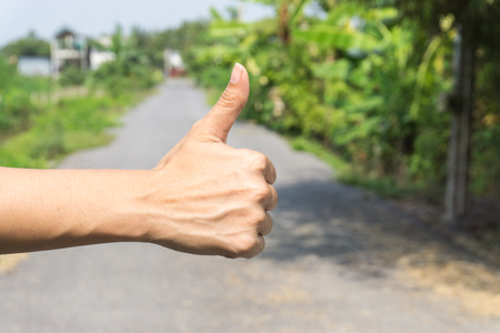 Close up of female hand showing thumbs up sign against on the street., hand sign help on the urban street after car crash.の写真素材