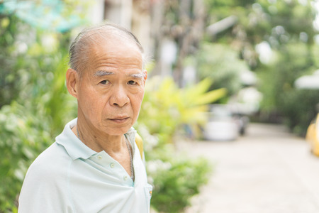 Old asian man glabrous head., Asia man stand at the street outside his home., with copy space for text.の写真素材