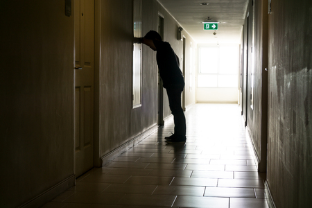 Silhouette of business man sitting alone., Sad and Serious Male sit and hug his knee alone of closeing office.With his reflect shadow. Dramatic moment. sad concept., hurt concept. lonelyの写真素材