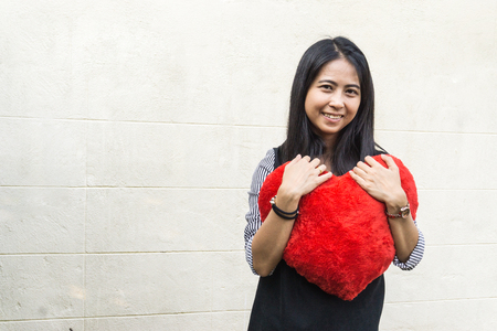 Beautiful asian woman with a big red heart shape pillow. valentine concept. love concept.の写真素材