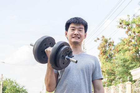 muscular young asian man lifting weights in park., healthy concept., sport concept.の写真素材