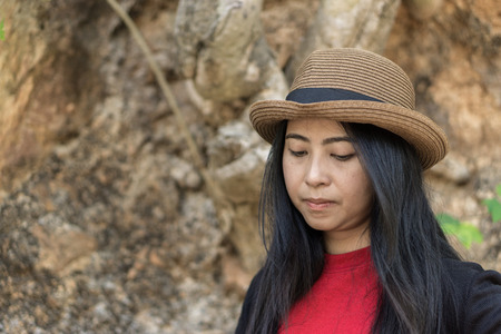 Smiling young woman travel outdoor in thailand., Portrait of young Asian girl., Asian female model poses on the mountain. with red clothes and hat in the summer in thailand.の写真素材