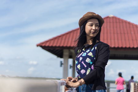 Outdoors portrait of young asia girl at natural background., Young Asian traveler girl chilling in the sun beside river and Waterfront pavilion and red roof., female travel at the chulachomklao Fortの写真素材