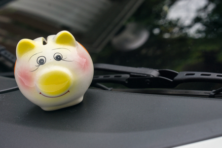 Small piggy money box on car bonnet at the street.,  Saving money concept.の写真素材