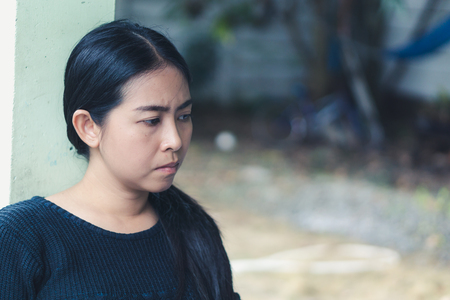 Asian woman is thinking about something at outdoor her home., serious concept.の写真素材