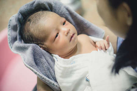 Newborn baby taking a bath by mother at home, asian child.の写真素材