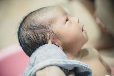 Newborn baby taking a bath by mother at home, asian child.の写真素材