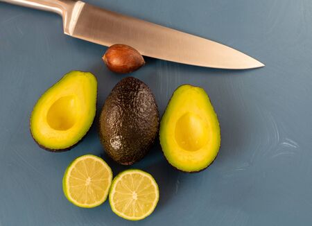 Two avocados and and a lime on blue bakcground, making guacamoleの写真素材