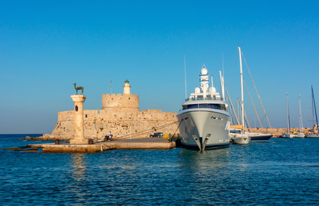 Fort of St. Nicholas and column with deer statue in Mandraki harbor of Rhodes, Greeceのeditorial素材