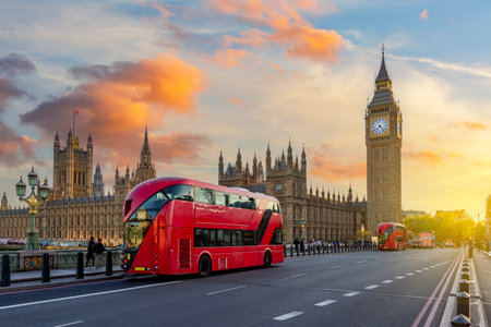 Double-decker buses on Westminster bridge and Big Ben tower at sunset, London, UK