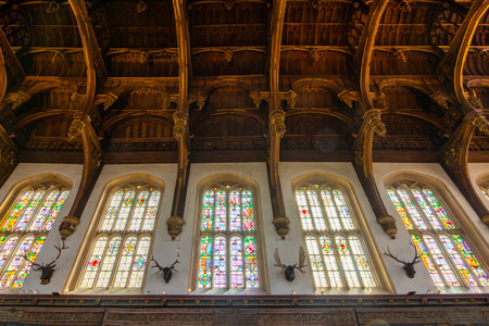 London, UK - Interior view of the Great Hall ceiling and stained glass windows at Hampton Court