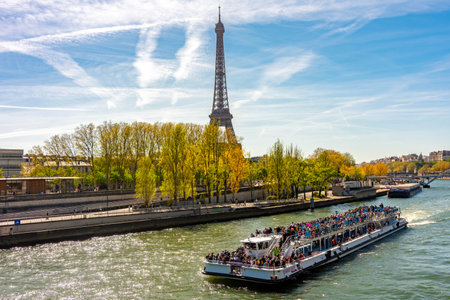 Paris, France - 06 April 2025: Tower and cruise boat sailing along Seine riverの写真素材
