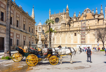 Seville, Spain - 28 March 2025: Horse carriages and Seville Cathedral on Triumph Squareの写真素材