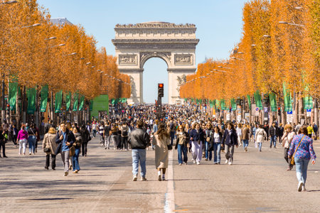 Paris, France - 06 April 2025: People walking on Champs Elysees avenue with Triumphal arch (Arc de Triomphe) at backgroundの写真素材