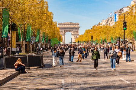 Paris, France - 06 April 2025: People walking on Champs Elysees avenue with Triumphal arch (Arc de Triomphe) at backgroundの写真素材