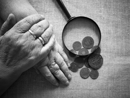 Hands of old woman, magnifying glass  and money.selective soft focus.The concept of poverty in retirement.の写真素材
