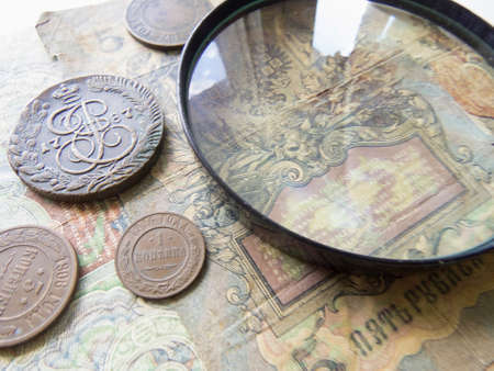 Pile of vintage metall (copper) coins. Magnifying glass and coins of the Russian Empire in the background kopyur. Antikvariat. Numismatics vintage backgroundの写真素材