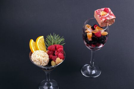 Holiday sweets and fruits in a glass and christmas toys on a black backgroundの写真素材