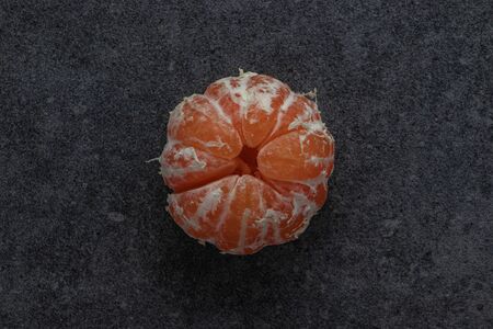 Single peeled tangerine on a dark background. Top view, copy spaceの写真素材