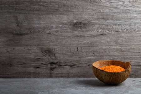 Red lentils in coconut shell on tile backgroundの写真素材