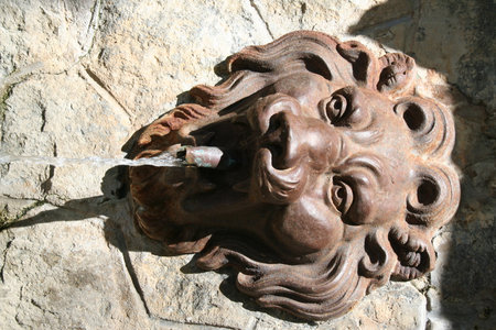 Sculpture of a face on a stone wall with flowing waterの写真素材