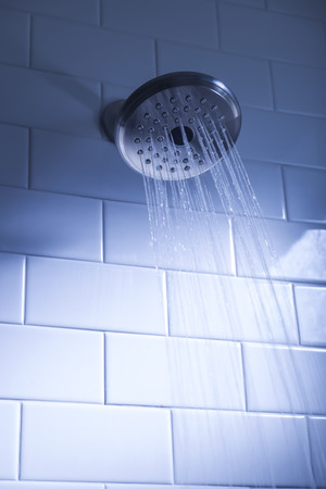 Shower head with water stream on blue backgroundの写真素材