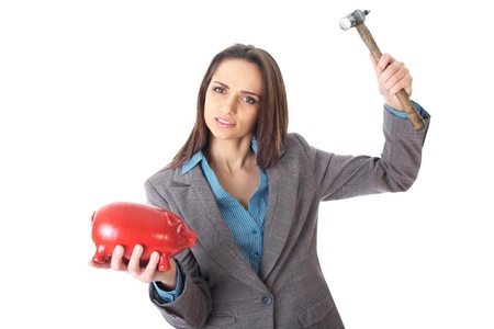 young redhead female trying to break into red piggy bank, spending your savings concept, isolated on whiteの写真素材