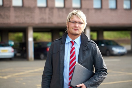 young blonde businessman with blurred office bulding as abckgroundの写真素材