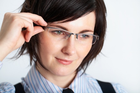 young brunette holds her glasses, studio shoot on grey backgroundの写真素材
