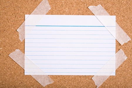 white stripped note card on cork board, holded by white tape on corners