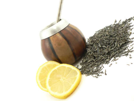 Some japanese green tea leaves closeup and on the background a cup