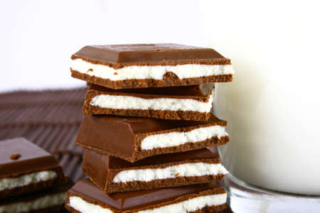 Pouring white milk against blue background and chocolateの写真素材