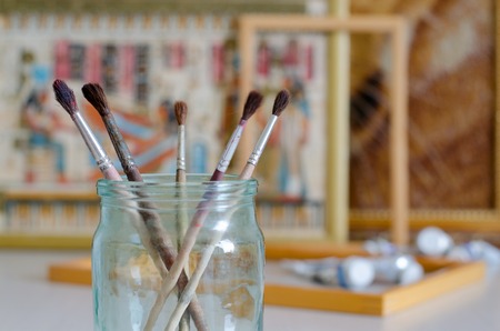Five paintbrushes in a glass jar. Blurred background - picture frames, paintの写真素材