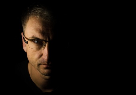Close-up portrait of a man with glasses. Black background with space for text. Nightの写真素材