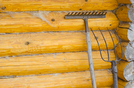 Old forks, rakes. Background - yellow wooden wall made of logs. Close-upの写真素材