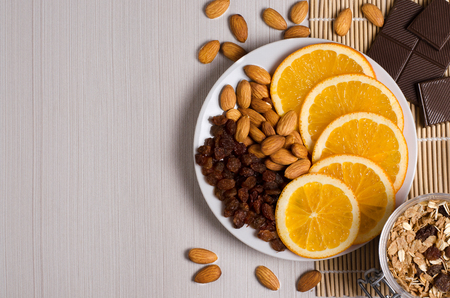 Healthy food. Fruit, homemade granola, nuts, chocolate on a white table. Flat top viewの写真素材