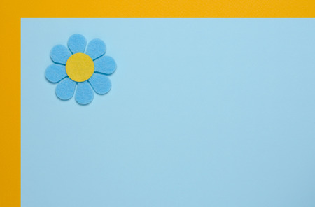 Blue flower made of felt on a blue and orange background. Greeting card. Space for textの写真素材