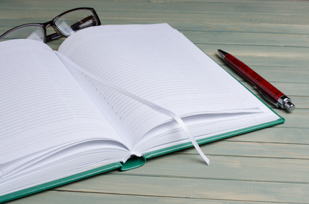 Notepad, glasses, fountain pen on wooden background. Close upの写真素材