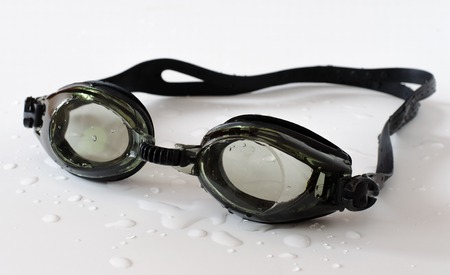 Black glasses for swim on white background. Water drops on the surface. Close upの写真素材