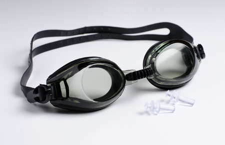 Black glasses for swim on white background, ear plugs. Close upの写真素材
