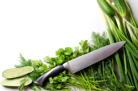 Green onions, dill, parsley, cucumbers, kitchen knife on white background. Flat top viewの写真素材