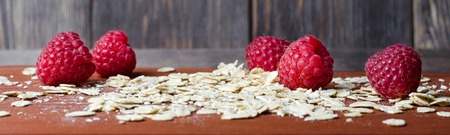 Red raspberry and oatmeal on a brown chopping Board. Horizontal photoの写真素材