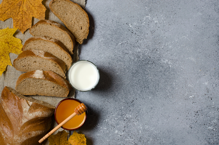 Rye bread is cut into pieces. Honey, milk in a glass Cup, yellow maple leaves. Copy spaceの写真素材