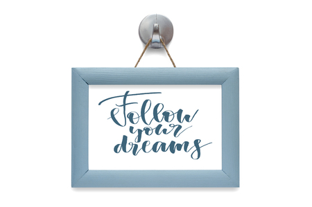 Follow your dreams - motivational quote. Stylized lettering. Blue wooden frame. Isolated on whiteの写真素材