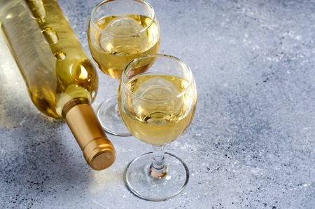 White wine in glass wine glasses, a bottle of wine. Blue background. Copy spaceの写真素材